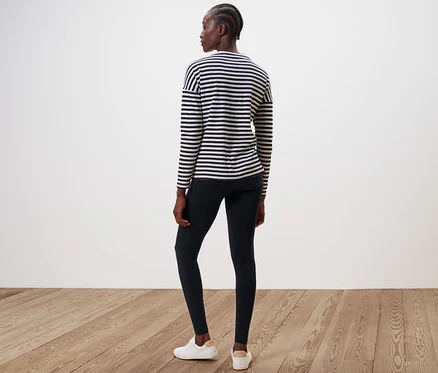 Une femme, vue de dos, porte un legging noir et un haut rayé.
