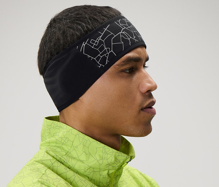 Homme portant un bandeau de protection contre le vent et une veste vert néon, les bras croisés.