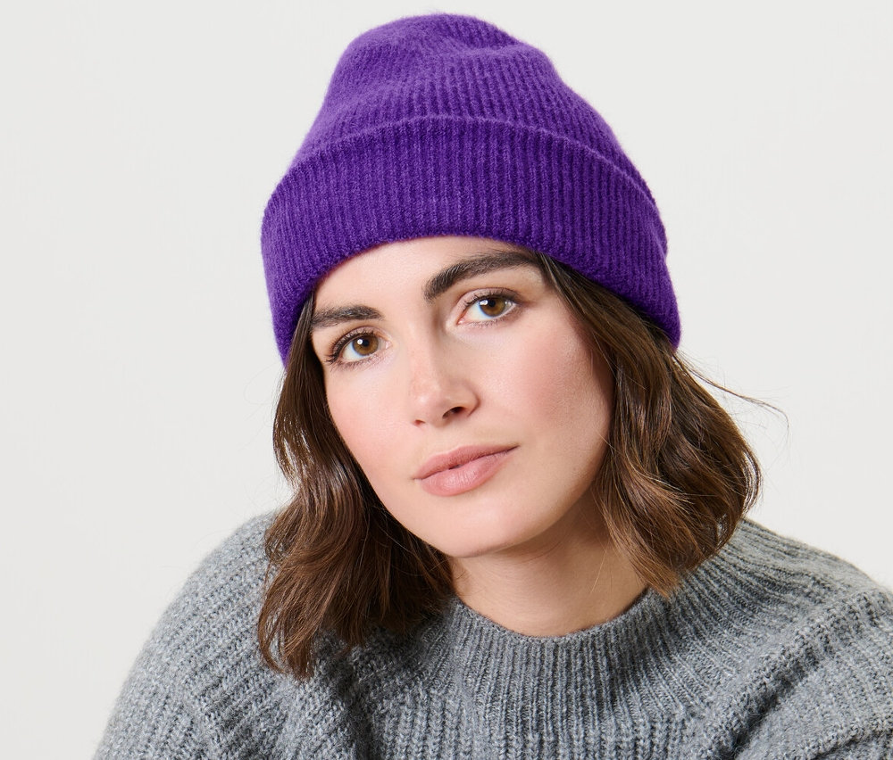Une femme assise portant un bonnet en maille violet.