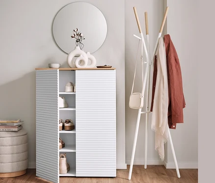 Armoire à chaussures avec porte ouverte à côté d'un porte-manteau et d'un pouf avec espace de rangement.