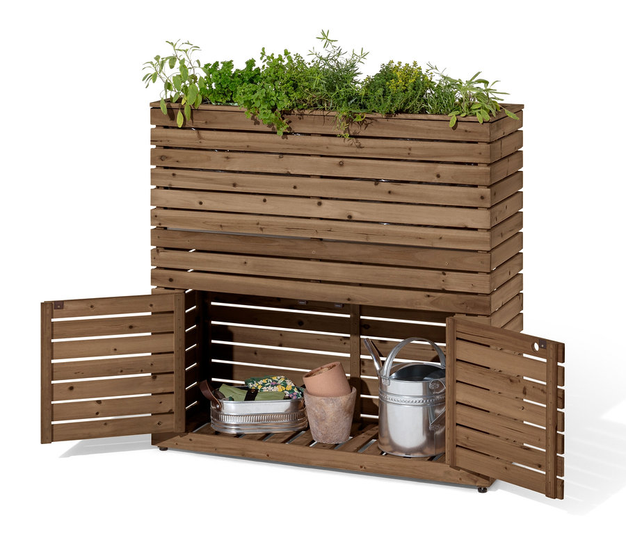 Séparateur de jardinière « Tinus » avec armoire de rangement. Il est planté de plantes vertes, les portes de l'armoire sont ouvertes et il y a un arrosoir argenté à l'intérieur.