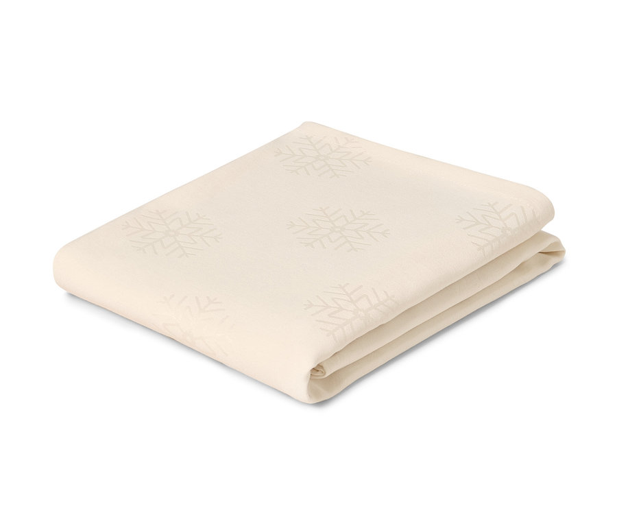 Nappe en jacquard crème pliée avec des motifs de flocons de neige.