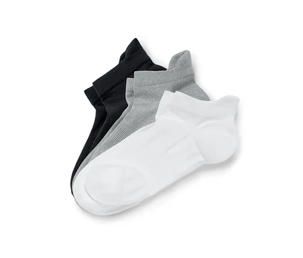 Trois paires de chaussettes de sport en noir, gris et blanc sont posées les unes sur les autres.