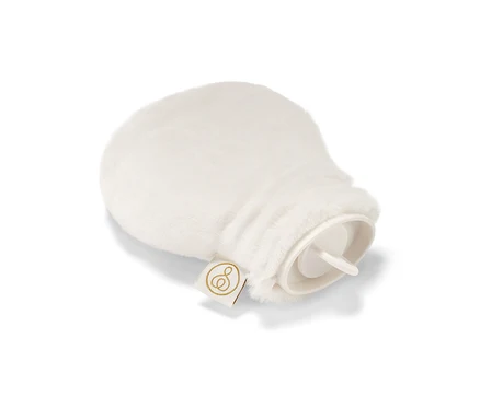 Une mini-bouillotte avec une housse en peluche blanche repose sur un fond blanc.