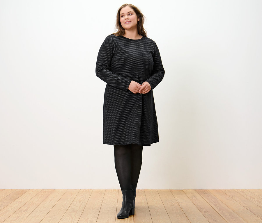 Femme debout portant une robe en jacquard scintillant.