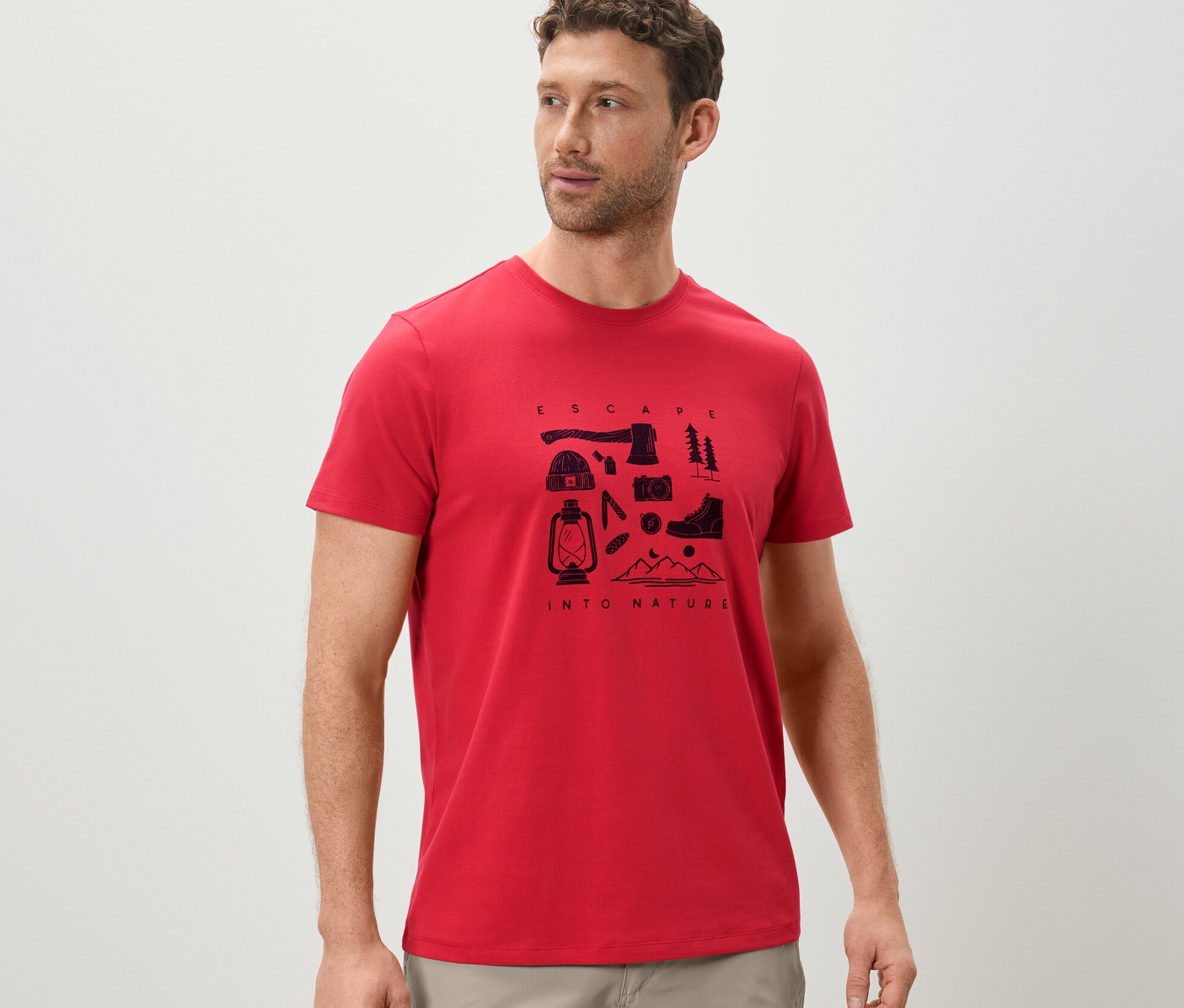 Un homme porte un t-shirt rouge imprimé sur le thème du camping.