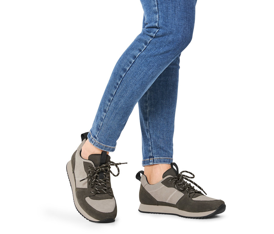 Jambes en jean bleu portant des baskets en cuir velours.