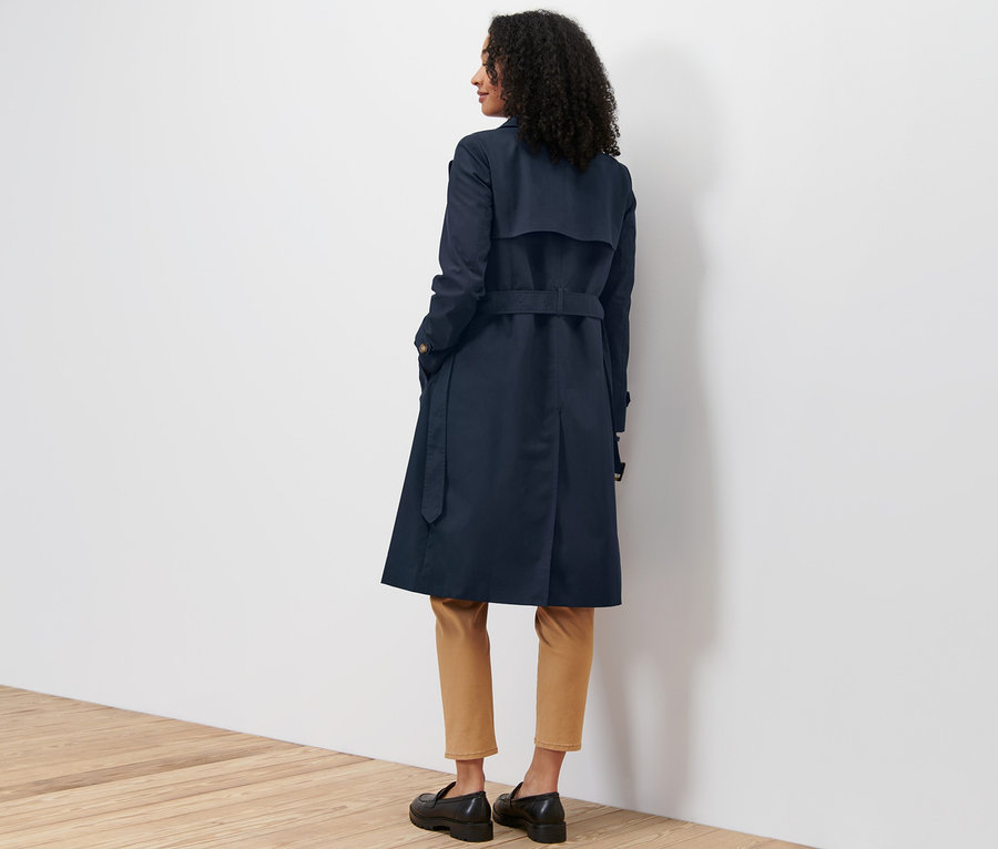 Une femme, vue de dos, porte un trench-coat bleu marine.