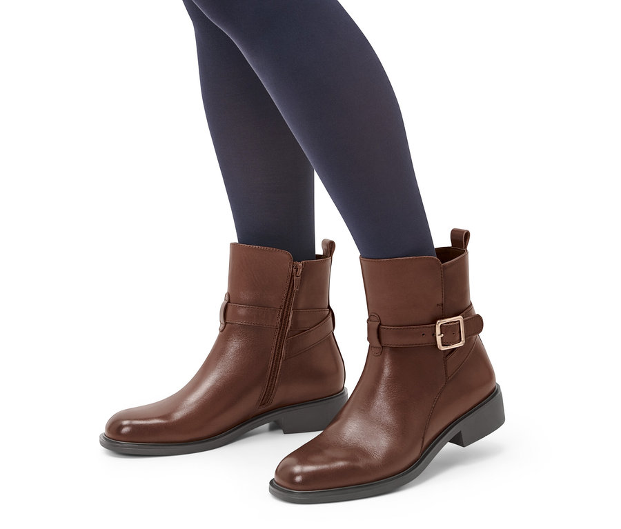 Jambes en collants bleu marine portant des bottines en cuir marron.