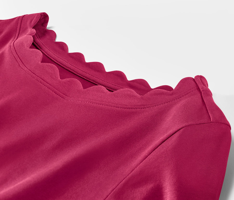 Gros plan sur un t-shirt rouge framboise à manches 3/4 et encolure festonnée.