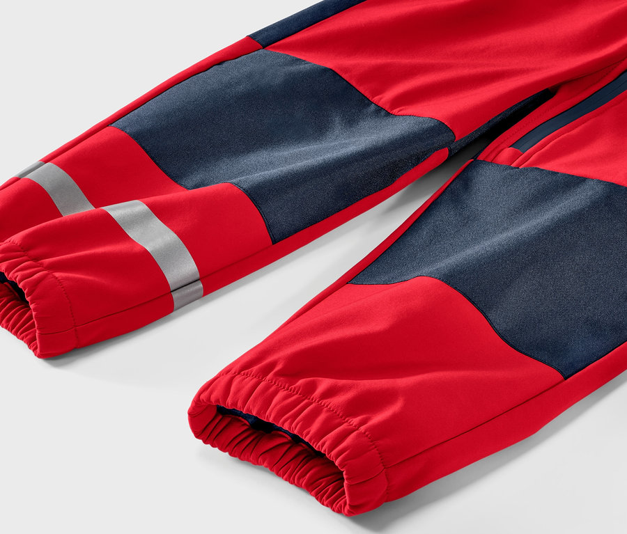 Détail d'une combinaison en softshell pour enfant, rouge et bleu.