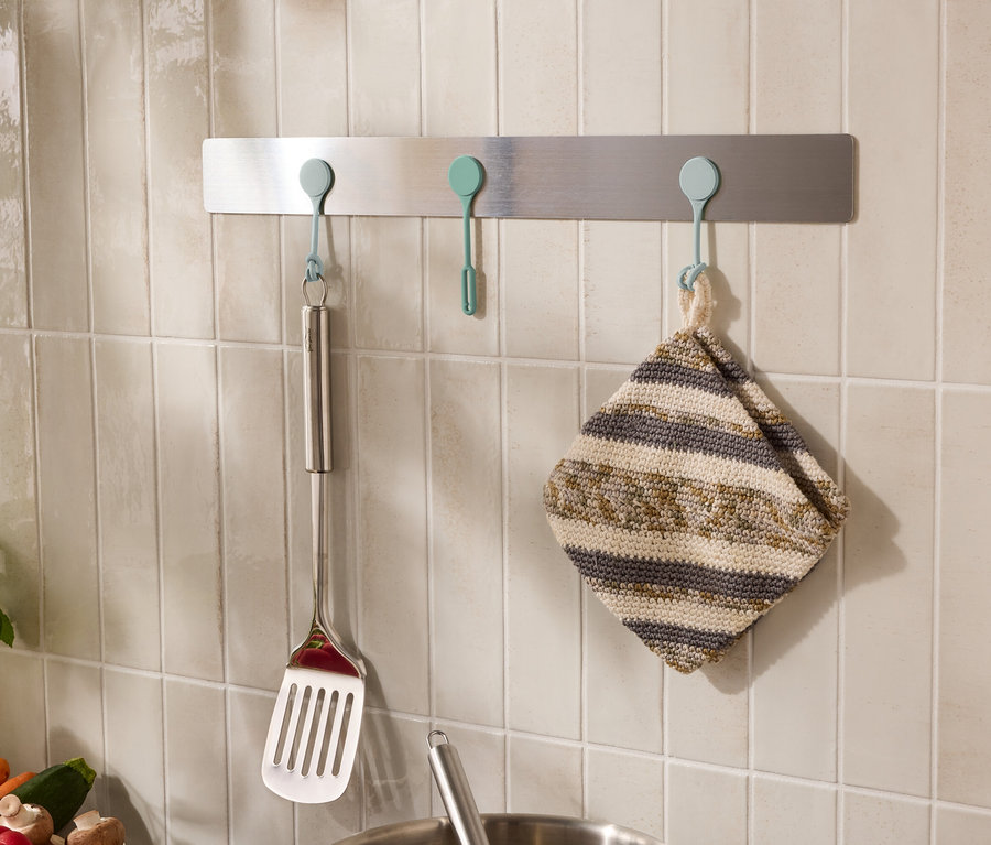 Des ustensiles de cuisine, comme une spatule et un torchon, sont accrochés à des crochets sur le mur.