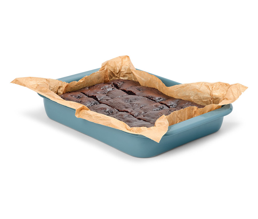 Brownies au chocolat dans un plat de cuisson bleu avec du papier sulfurisé.