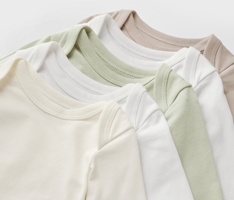 Vue détaillée de cinq bodys évolutifs pour bébé en beige, blanc et vert clair.