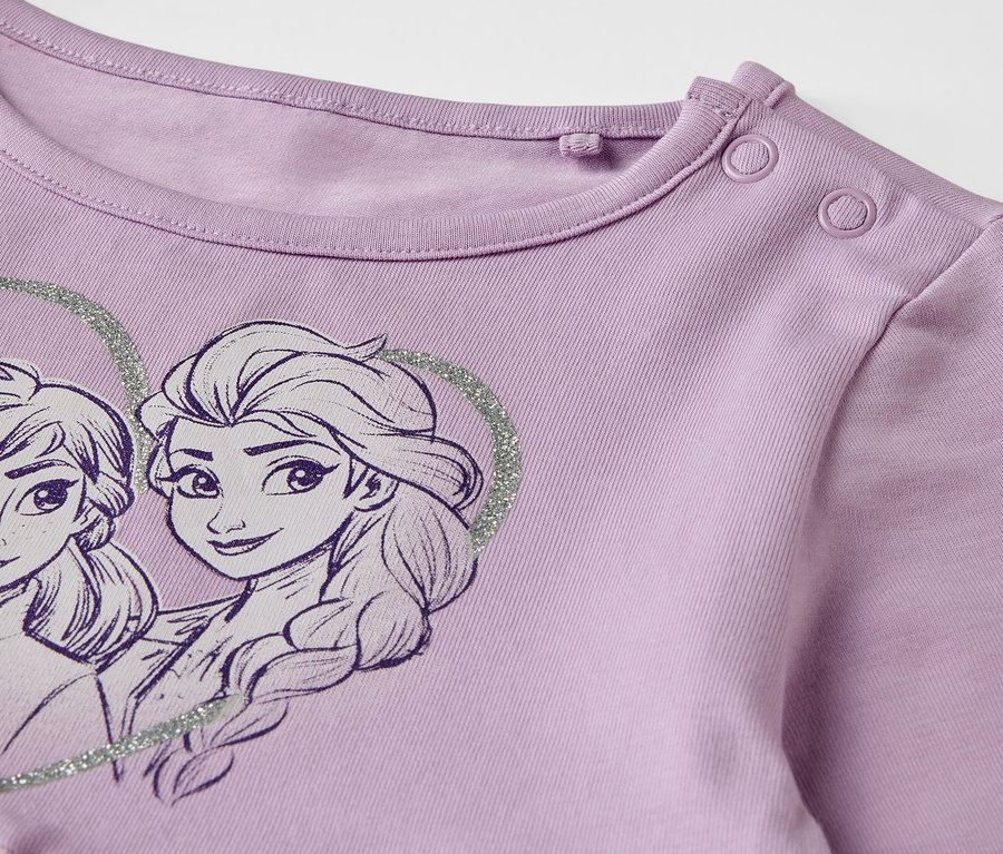 Gros plan sur une robe en jersey violette pour enfant, ornée d'Elsa et Anna.