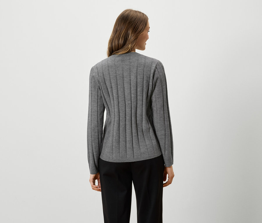 Femme vue de dos portant un haut gris à manches longues et un pantalon noir.