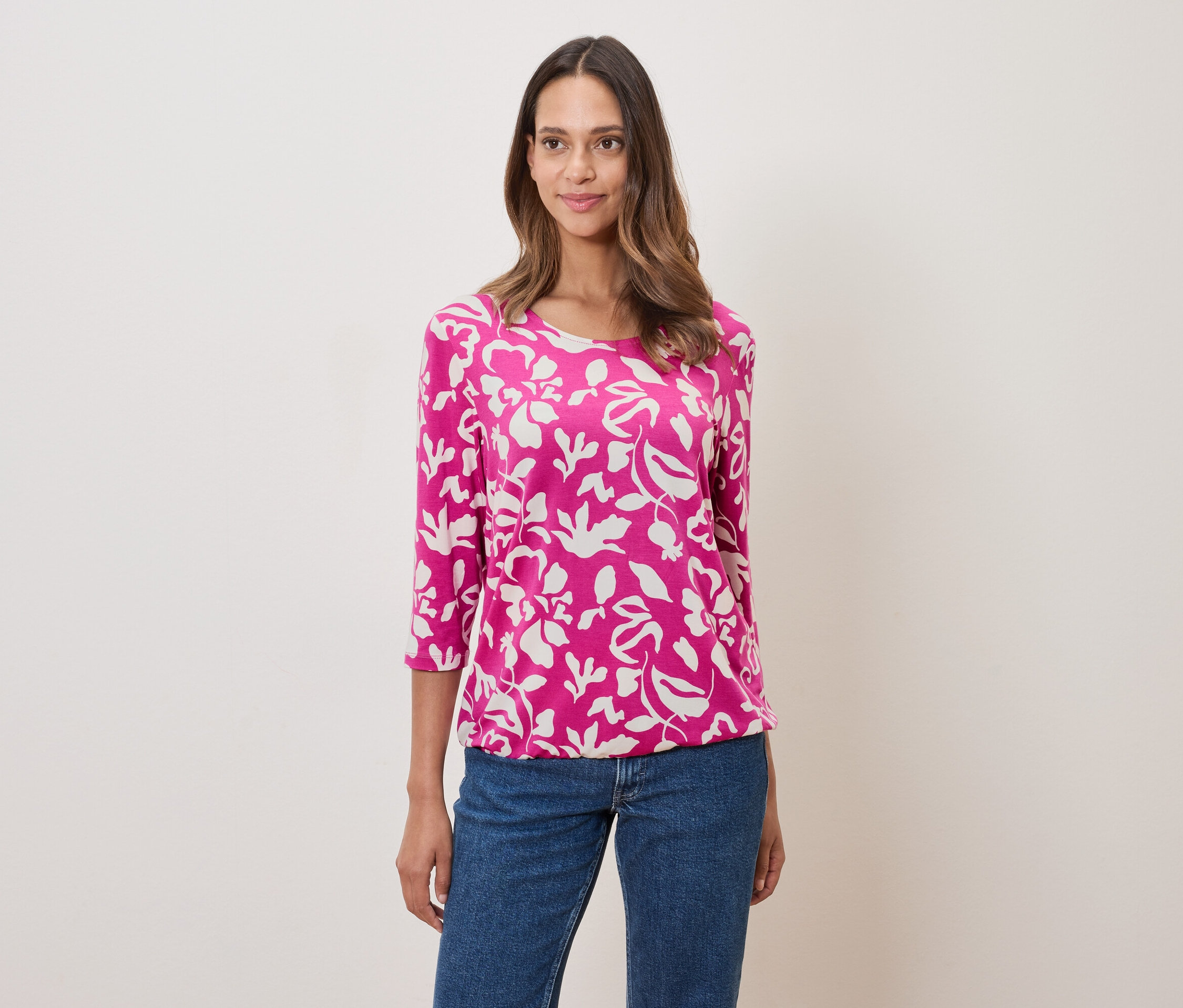 Femme portant un haut rose à motifs floraux et un jean.