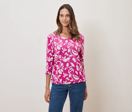 Femme portant un haut rose à motifs floraux et un jean.