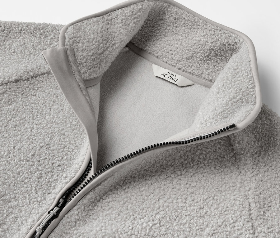 Gros plan d'un pull en polaire gris avec fermeture éclair ouverte et étiquette.