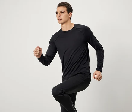 Homme en tenue de sport noire avec haut à manches longues et pantalon en train de courir.