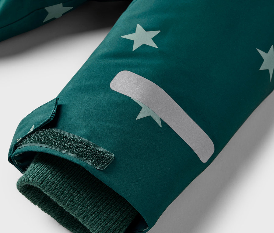 Détail de la manche d'une veste avec des étoiles et une fermeture velcro.