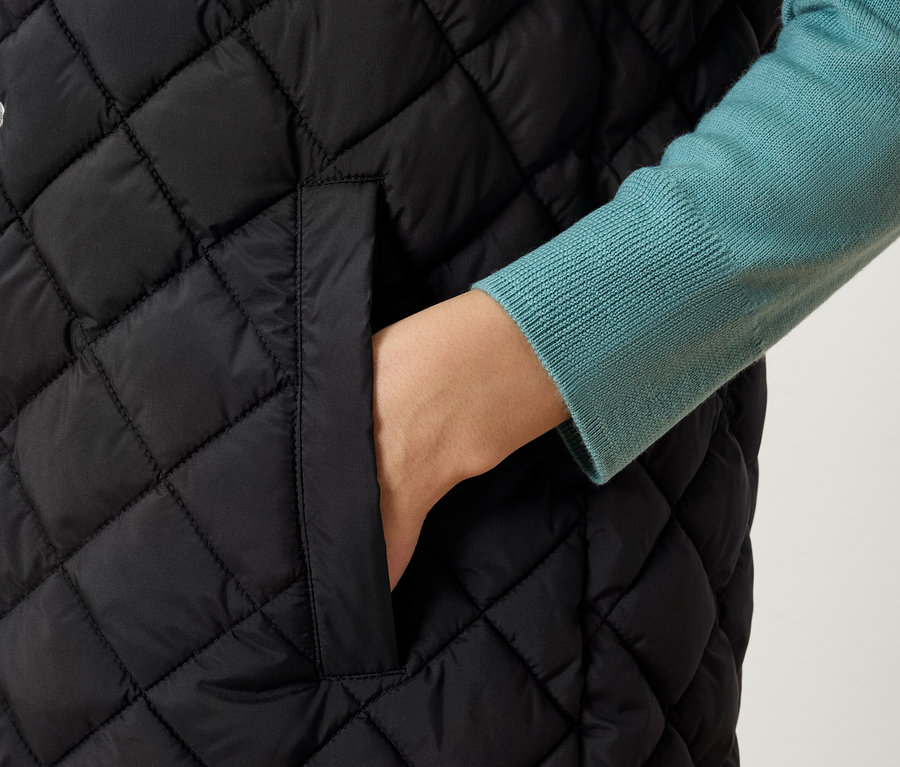 Gros plan d'un gilet matelassé pour femme avec une main dans la poche.