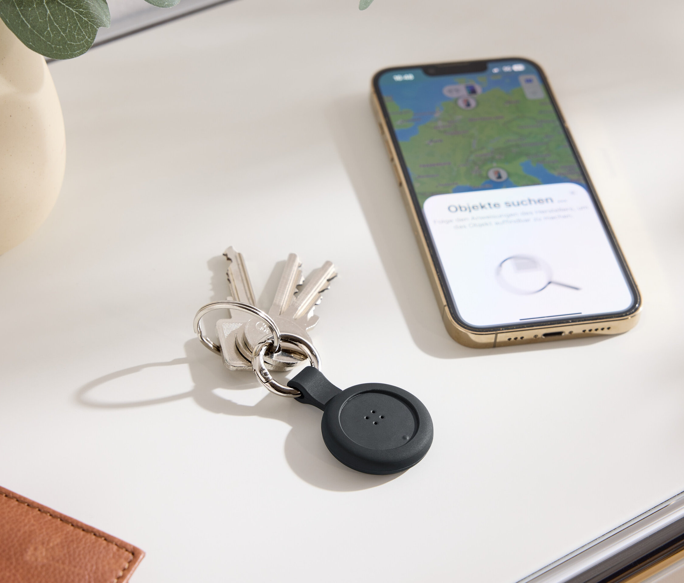 Des clés avec un traceur noir et un téléphone portable avec une carte sur l'écran sont posés sur une table.