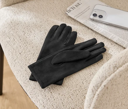 Sur une chaise beige sont posés une paire de gants en cuir noirs, un journal et un téléphone portable.