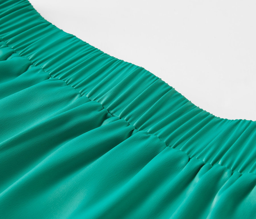 Gros plan sur une jupe en satin verte avec une taille élastique.