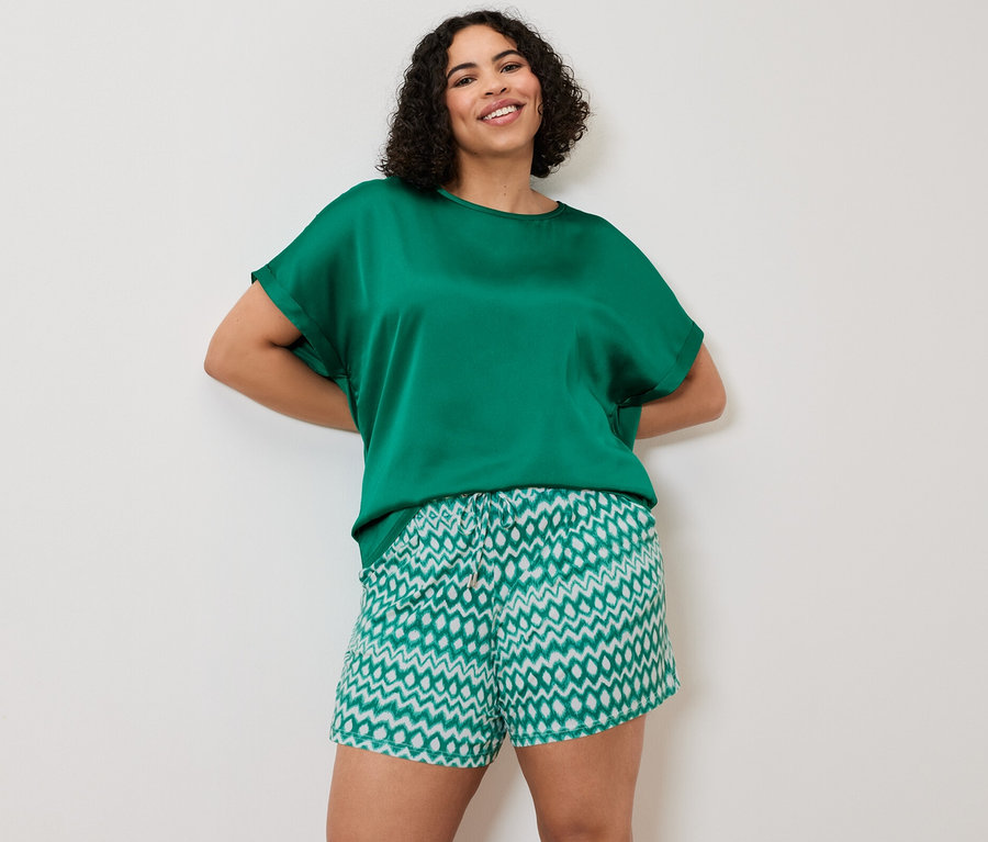 Femme posant dans un chemisier bimatière, turquoise, et 2 shorts en jersey.