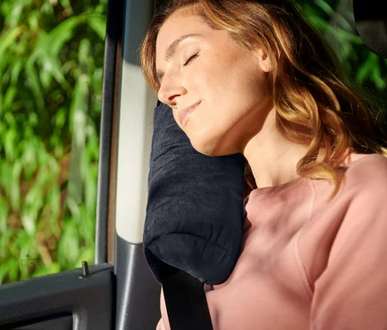 Femme dormant avec un oreiller cervical dans la voiture, ceinture de sécurité attachée.