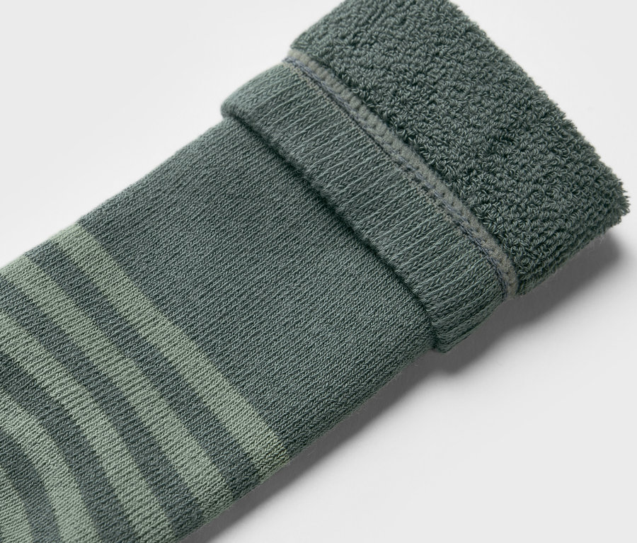 Gros plan d'une chaussette pour bottes en caoutchouc pour enfants (2 paires), motif camions, avec des rayures vertes et un ourlet retroussé.