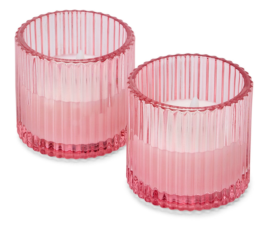 Deux bougeoirs cylindriques roses en verre avec une texture côtelée se tenant sur un fond blanc.
