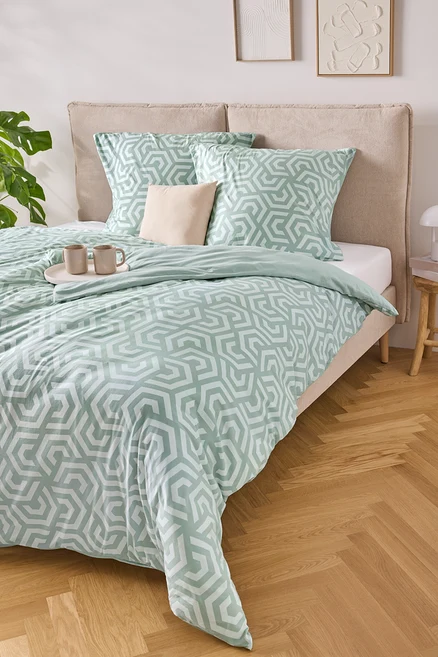 Un lit avec des draps rayés bleu clair et blanc, deux oreillers et un plateau avec deux tasses dessus.