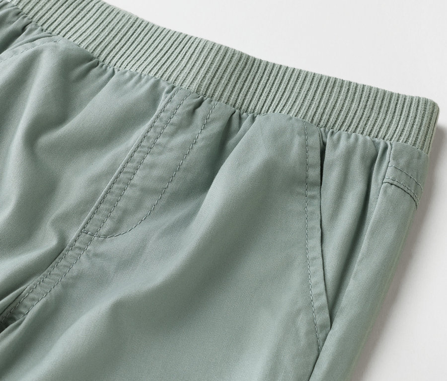 Gros plan d'un pantalon vert clair avec une taille élastique.