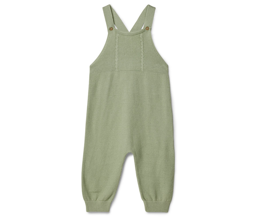 Un seul vêtement de bébé tricoté vert clair avec des bretelles est posé sur un fond blanc.