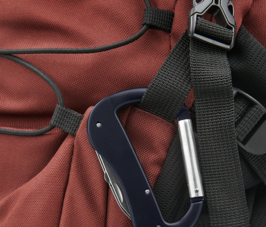 Gros plan d'un mousqueton avec un outil multifonction, fixé à un sac à dos rouge.