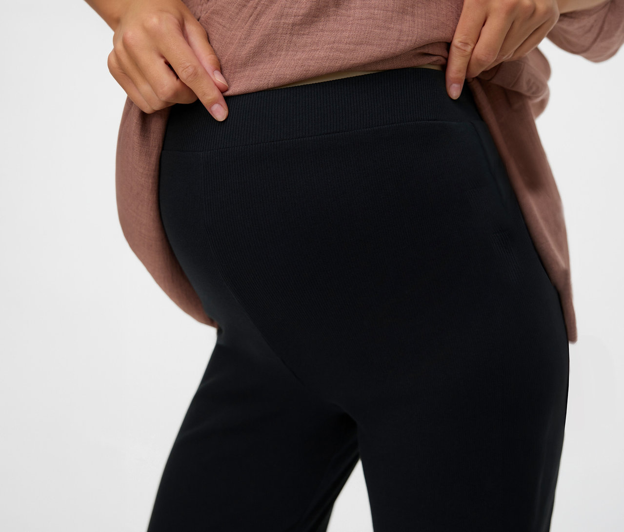 Femme montrant la taille du legging décontracté noir « MLEMILY » de MAMALICIOUS.