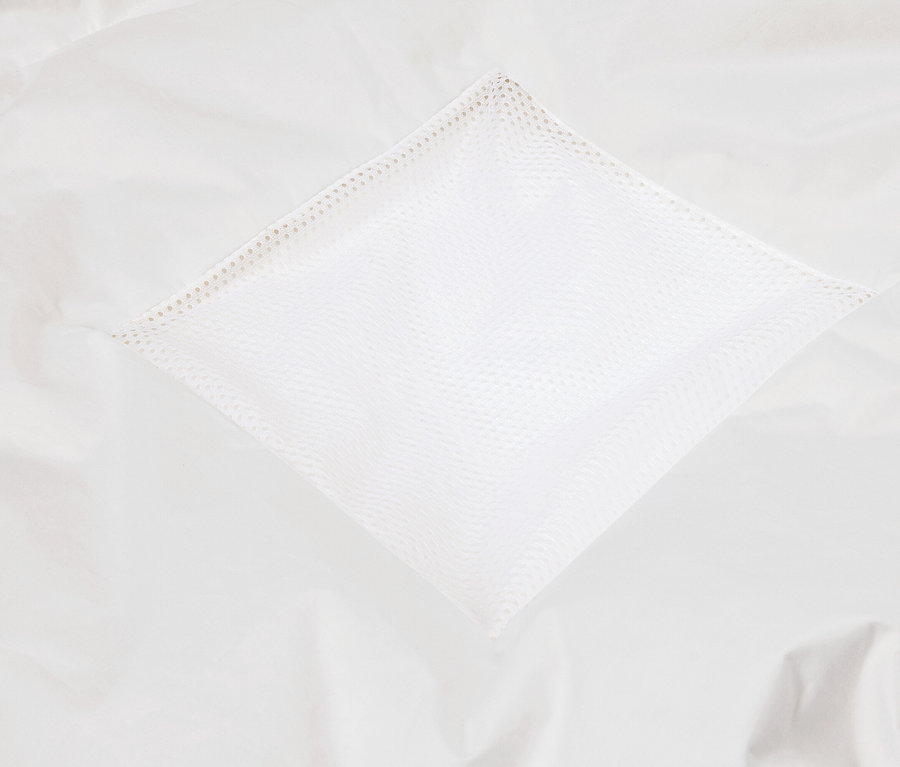 Gros plan d'une poche en tissu blanc avec une structure en filet sur un fond en tissu blanc.
