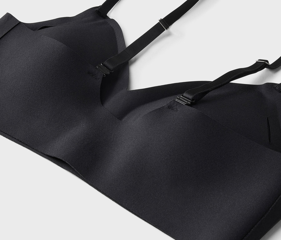 Gros plan d'un soutien-gorge noir à bretelles réglables sur fond blanc.
