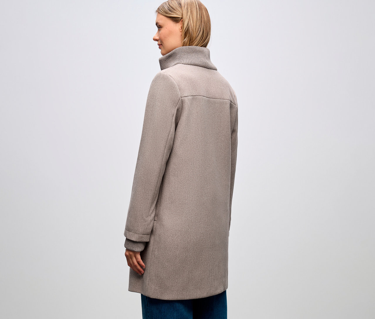 Femme de profil, portant un manteau court Street One et un jean bleu.