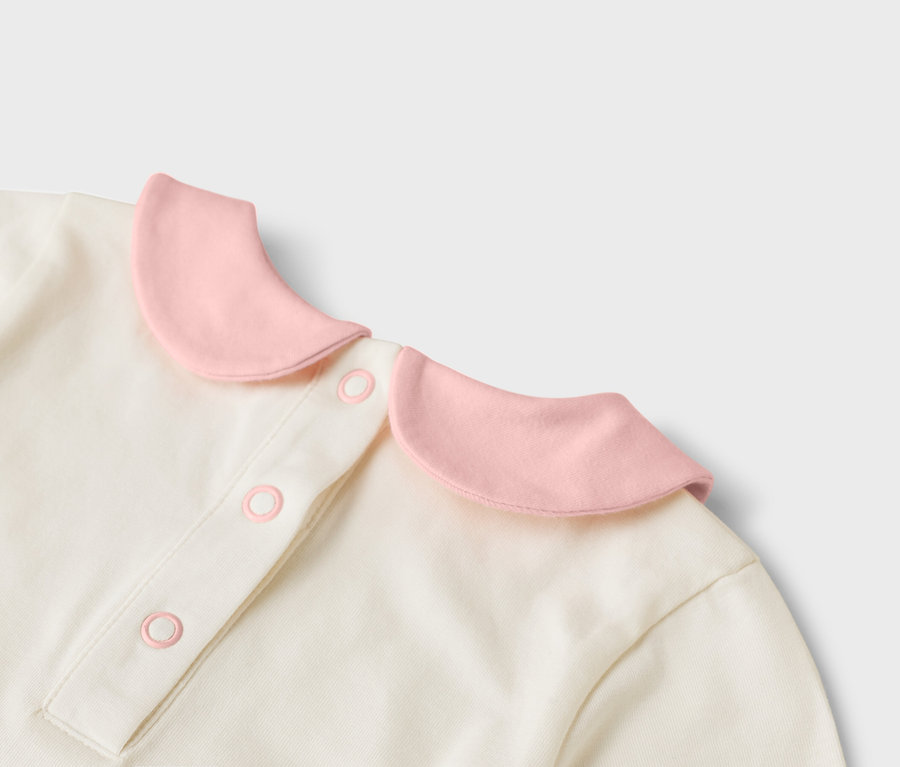 Gros plan sur un haut crème avec un col rose et des boutons.
