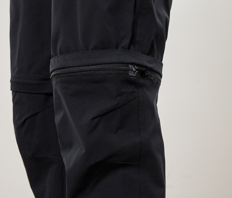 Gros plan du bas d'un pantalon noir avec une fermeture éclair sur la jambe.