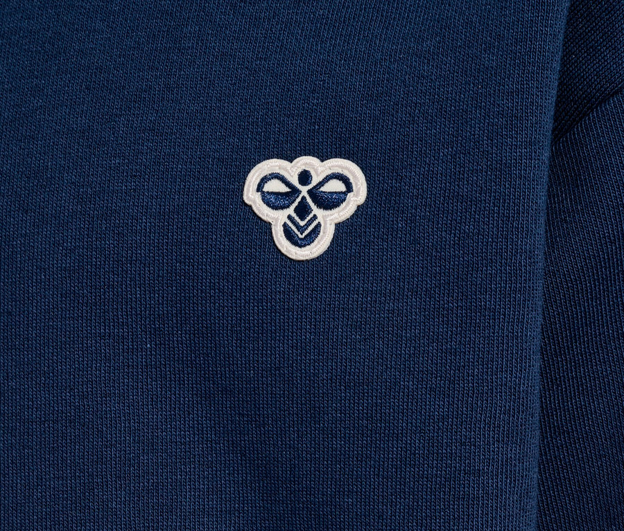 Gros plan d'un sweat-shirt bleu marine avec un petit logo blanc brodé sur la poitrine.