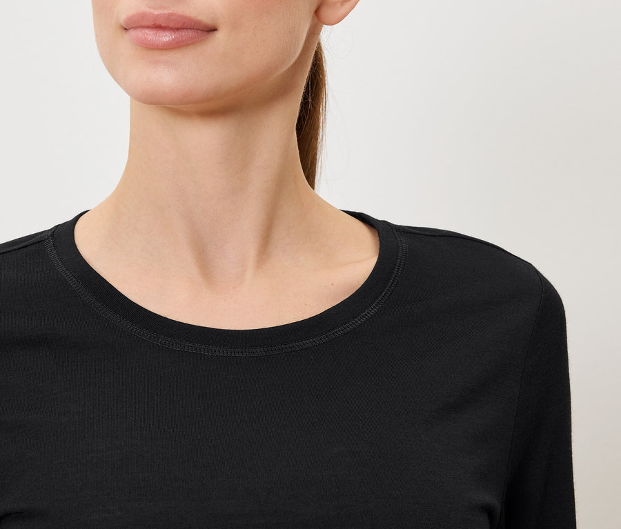 Gros plan d'une femme portant un T-shirt noir à manches longues.