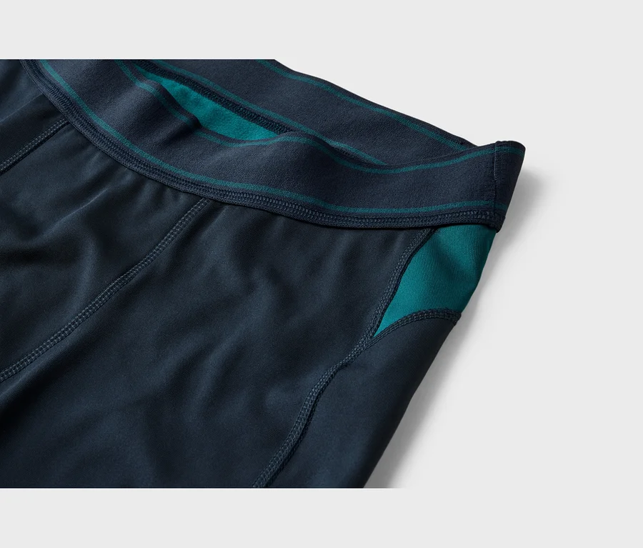 Gros plan d'un short ou legging de sport bleu foncé avec une taille élastique marine et des accents turquoise sur la taille et le panneau latéral.