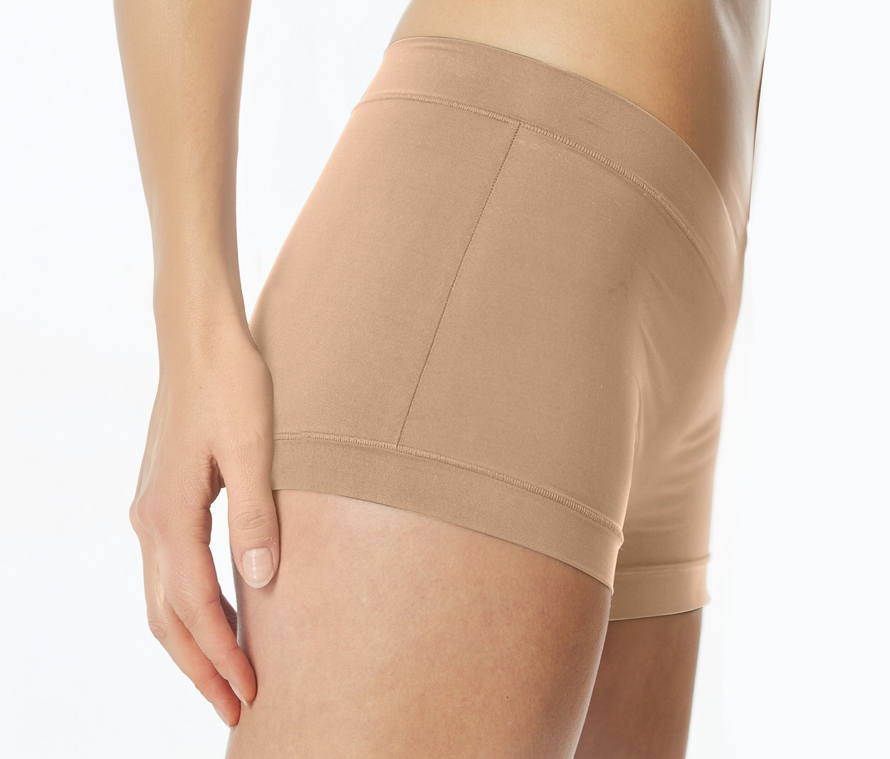 Femme portant un shorty beige clair, sa main gauche posée sur sa cuisse.