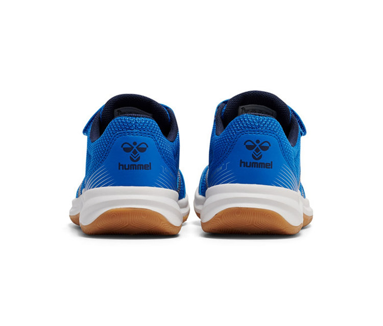 Deux chaussures de sport Hummel bleues avec des semelles blanches et des semelles extérieures marron, vues de l'arrière, sur fond blanc.