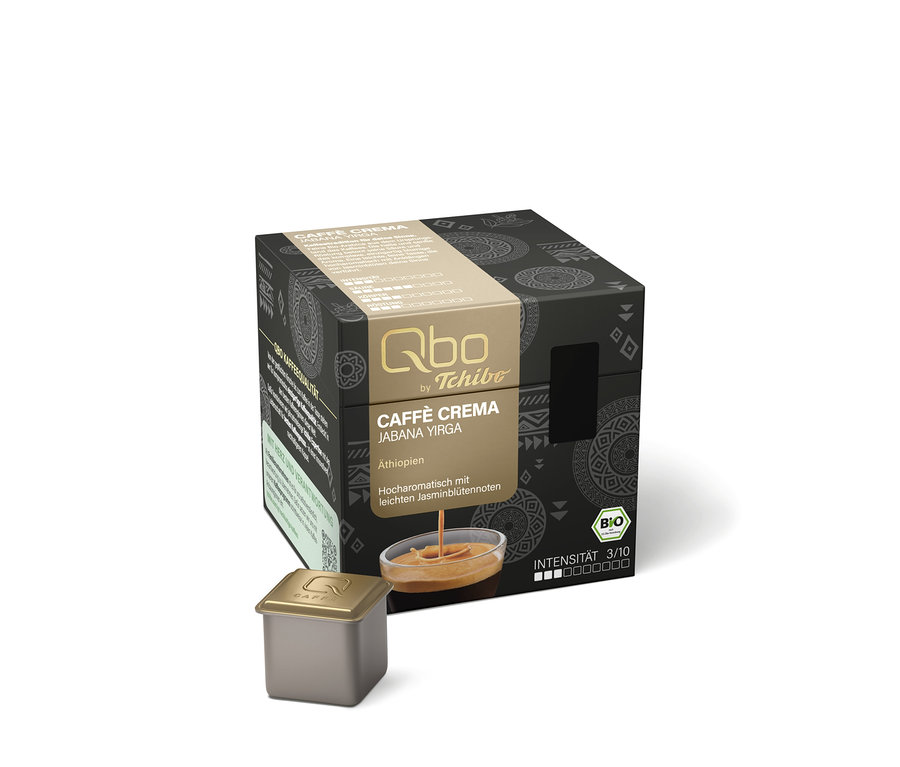 Emballage cubique foncé pour capsules Qbo Caffè JABANA YIRGA avec une bande dorée affichant le nom du produit, l'origine Éthiopie, des notes de fleurs de jasmin, le logo BIO et l'intensité 3/10. Une image de café avec de la crème est sur la bande. Une capsule de café dorée est posée devant.