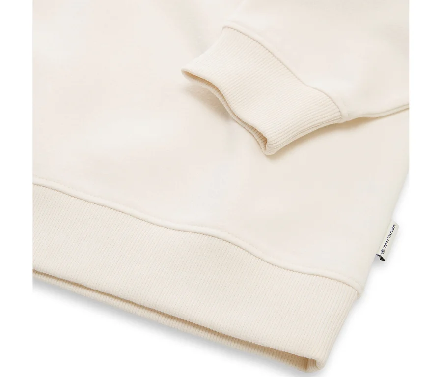 Sweat-shirt couleur crème avec poignets et ourlet côtelés, affichant une petite étiquette de marque « TOM TAILOR » sur le côté droit.